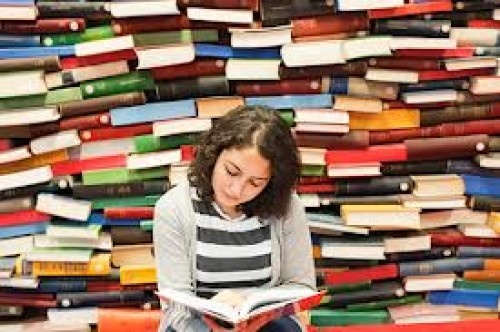 A girl reading a book in front of a wall of books